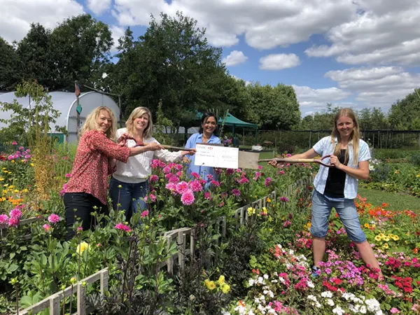 Volunteers amongst the flowers at Jealotts Hill with a donation cheque